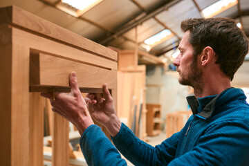 Carpenter In Workshop Gluing Wood To Window Frame