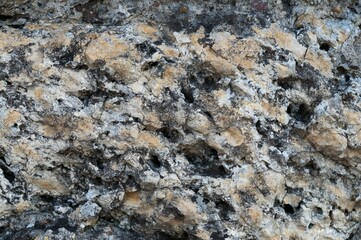 this image shows a gray, rock like surface with small scratches and some black and