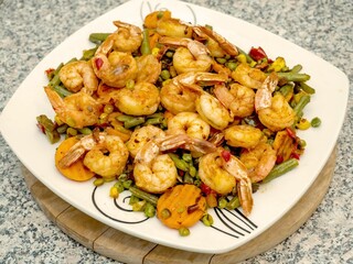 Close-up of a large bowl filled with cooked shrimp and a variety of vegetables