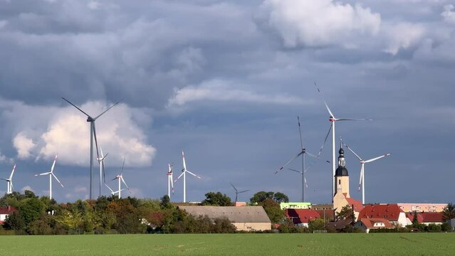 Wind turbines and the bell tower of Zeithain parish church against overcast sky in Zeithain, Germany