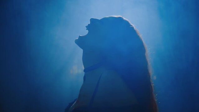 art black silhouette close-up fantasy vampire girl screams growls shows sharp white teeth fangs lips beauty face gothic woman in moon light night fog dark room sexy lady long red hair fly slow motion