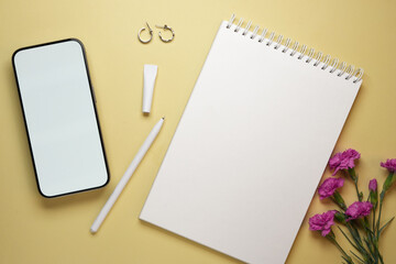 Feminine stationery composition. Smart phone, notebook with pen and pink carnation flowers. Top view, flat lay. Mockup. 