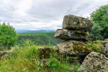 Three stones lie on top of each other on an ancient wall. Tetralith. Khrami canyon. Samshvilde, Georgia