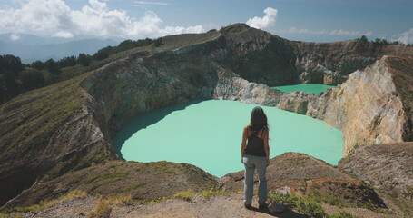 Woman looking on volcano mountain crater edge. Volcanic Kelimutu blue crater lake. Travel...