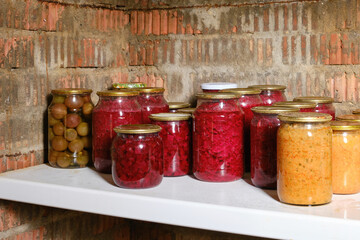 Jars of pickled vegetables. Canned jars of fruit and vegetables in the cellar. Selective focus