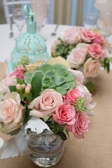 Table is adorned with fresh pink roses and white flowers, set up at a wedding reception