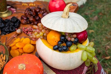 Closeup of a pumpkin filled with fruits on the table outdoors