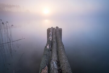 Wooden jetty in the pond on a foggy day
