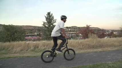 Slow motion shot of a young Caucasian male bicycle-rider riding his bicycle on an unpaved dirt trail