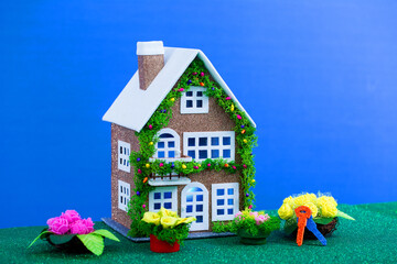 A toy brown house decorated with New Year's artificial garland with blue light in the windows...