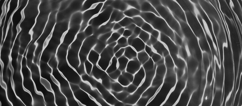 Abstract Black water surface texture natural ripple background. clear water wave texture on black background. Sunlight effect on surface of defocus blurred water. summer or spa concept
