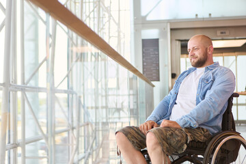 Man in a wheelchair enjoying the view in a modern building, reflecting on accessibility and...