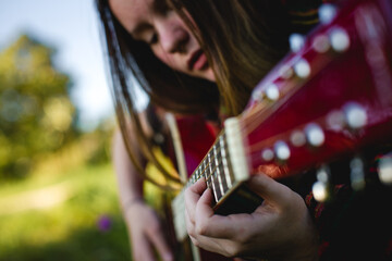A girl immersed in playing the guitar, highlighting the intricate details of her fingers on the...