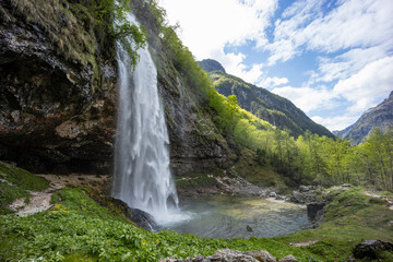 Fontanon of Goriuda, Udine. Wonderful waterfall that falls from a cliff. The force of the waterfall is a sight to behold. Hiking, trekking in the open area surrounded by woods. Summer holidays, peace.