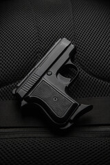 A small semi-automatic pistol on a dark background. Weapons for concealed carry and self-defense. Short-barreled weapon.