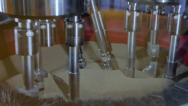 Drag finishing machine uses abrasive particles for polishing and cleaning metal details clamped in rotating holders at factory, plant: close up. Metalworking, industrial and deburring concept