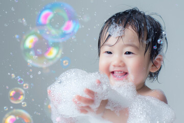 Adorable toddler is filled with glee while playing with iridescent soap bubbles and frothy foam against a light background, children skincare