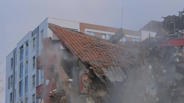 Slow motion: demolition of building, moment of roof collapse: excavator with hydraulic crusher is tearing down the old typical Turkish multi-storey apartment, residential building in Istanbul, Turkey