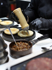 cocinero echando salsa de mahonesa con sus manos y guantes al pan brioche para elaborar hamburguesas