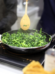 elaboración de guiso con espinacas en la sartén del fogón