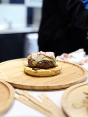 meat burger, melted cheese, and bacon freshly cooked and presented on a wooden board