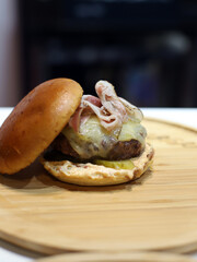hamburguesa gourmet artesanal de carne, queso fundido y beicon presentada en una tabla de madera