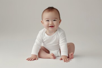 Fototapeta premium Adorable Smiling Asian Baby Sitting on Soft Neutral Background