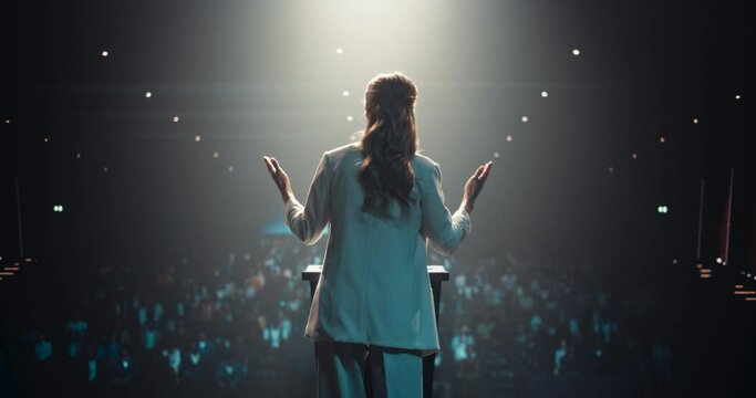Static Shot of an Excited Female Entrepreneur Shares an Insightful Talk on Technology and Leadership at a Professional Business Conference. Diverse Multiethnic Guests Sitting in a Dark Auditorium