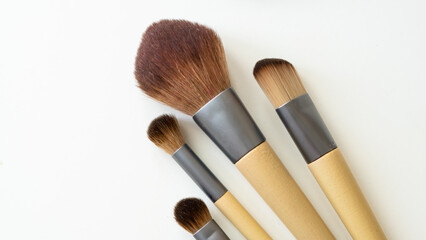 Wooden organic makeup brushes on white backdrop. Eco-friendly