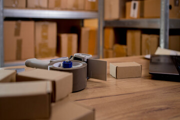 Composition with packing tape dispenser, laptop and paper boxes on composition of parcels