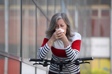 Fototapeta premium Senior woman has allergy, Woman sneezing in front of blooming