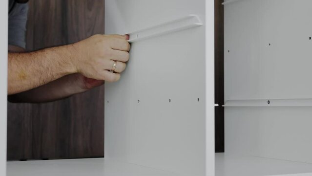 Installation of a drawer on guides in a cabinet. Furniture assembler by handyman.