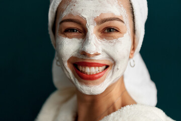 Fototapeta premium Portrait of a beautiful girl in the studio in a bathrobe and with cream on her face. Grain effect used
