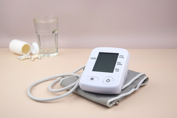 Digital blood pressure tonometer and pack of pills on a light background with copy space.