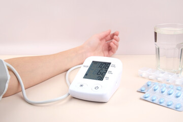 Digital blood pressure tonometer and pack of pills on a light background with copy space.