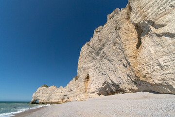 Fototapeta premium Etretat cliffs and beach in the Normandie region of France in a sunny day. Falaise d'amont chalk clliffs in the Alabaster coast.