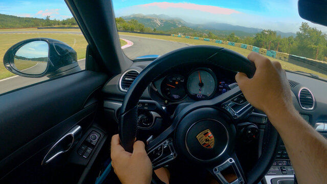 POV: Racing along an empty asphalt racetrack in a powerful Porsche sportscar.