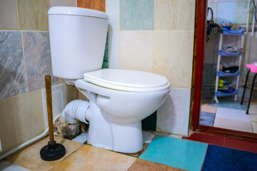 A serviceman is repairing a toilet with a hand plunger caused by a clogged toilet.