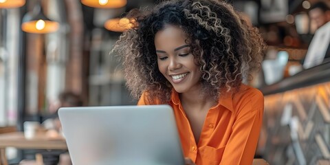 Joyful Black woman with curly hair typing on laptop in a cafe. Concept Black woman, Curly hair, Laptop, Cafe, Joyful