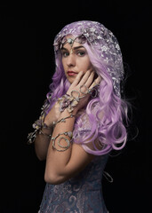 artistic portrait of beautiful female model with long purple hair wearing a flowing fantasy cloak. ...