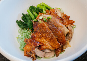 Close-up Thai delicious noodles, roasted duck over green noodles or jade noodles in white bowl. View from above.