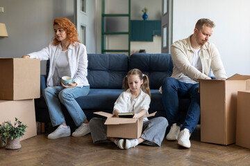 Upset daughter helping mom and dad packing belongings in cardboard boxes, relocating sitting on...