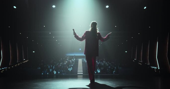 Celebrity Public Speaker Giving an Inspiring Talk at an International Business Development Conference. Female Walking on Stage with a Microphone to Deliver a Strong Message and Coaching Advice