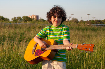 Child boy playing guitar outdoors