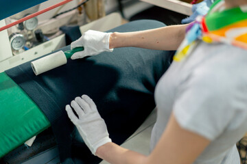 top shot close up professional dry cleaner young girl uses an adhesive roller to remove wool on a black jacket 