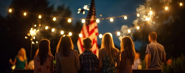A familys silhouette against a litup American flag in the backyard during a 4th of July party