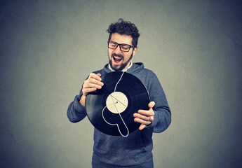 Happy singing young man listening music on  a vinyl record 