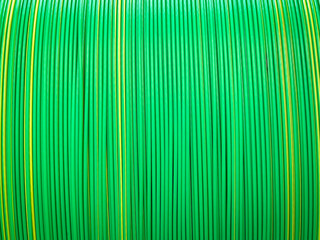 Vivid green and yellow plastic coated cables tightly coiled, showcasing a symmetrical and colorful pattern.
