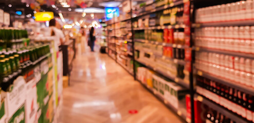 Abstract blurred supermarket aisle with colorful shelves fruit and unrecognizable customers as background.