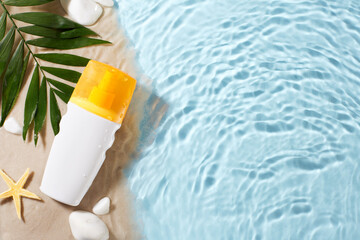 Sunscreen bottle with droplets beside tropical leaves on sandy shore, near pool water. Ideal for articles and ads about sun protection and beach essentials